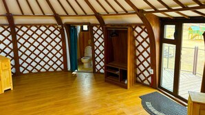 An interior with a wooden floor, a wooden bench, a wooden cabinet, a hanging coat rack, and a view of an outdoor play area through a large window. - Khumug Tour Resort (Ulaanbaatar)