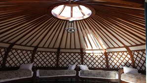 A yurt with three wooden beds, a central hanging light fixture, and a lattice ceiling design. - Khumug Tour Resort (Ulaanbaatar)