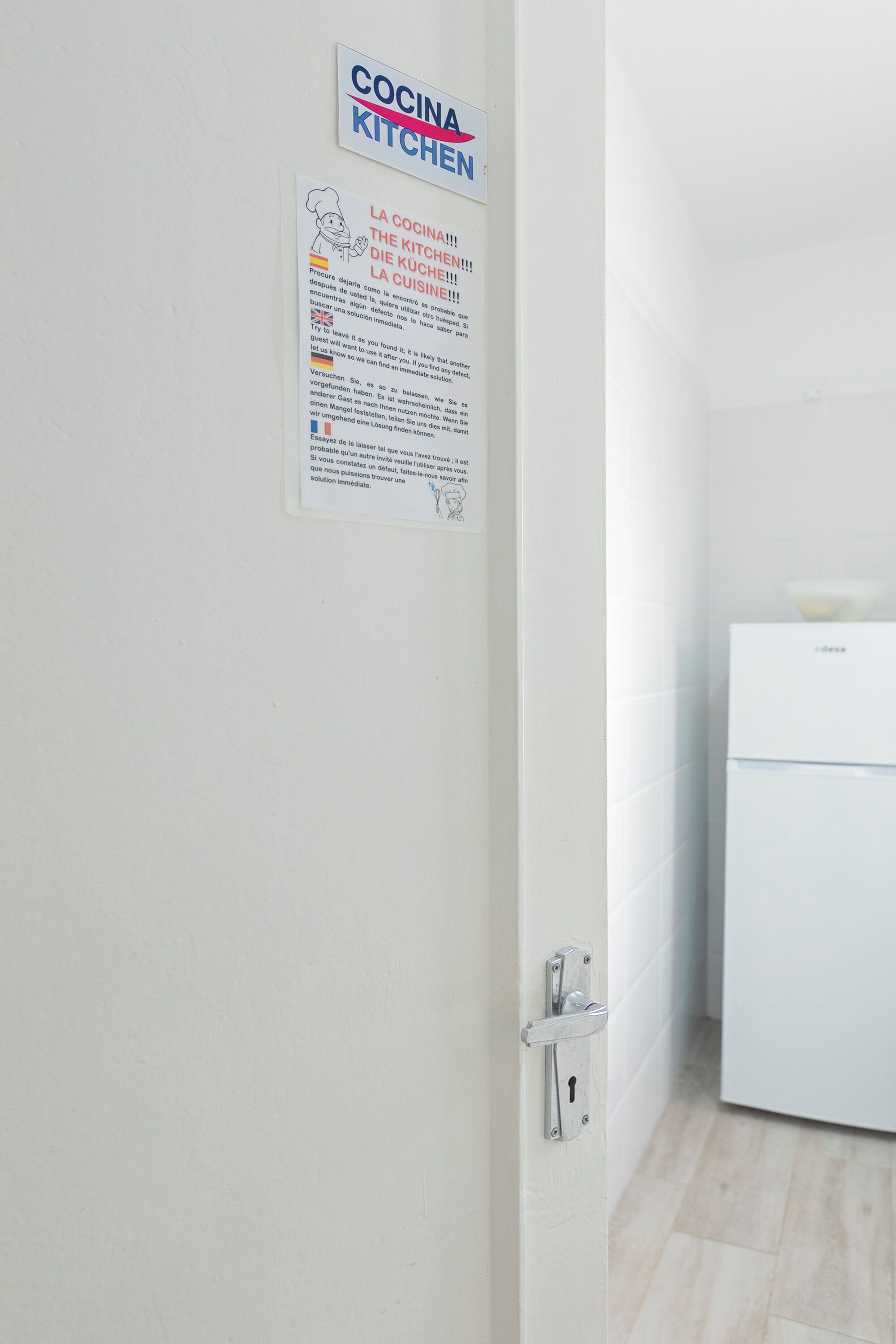 Un área de cocina con un refrigerador blanco y una puerta con cerradura.
