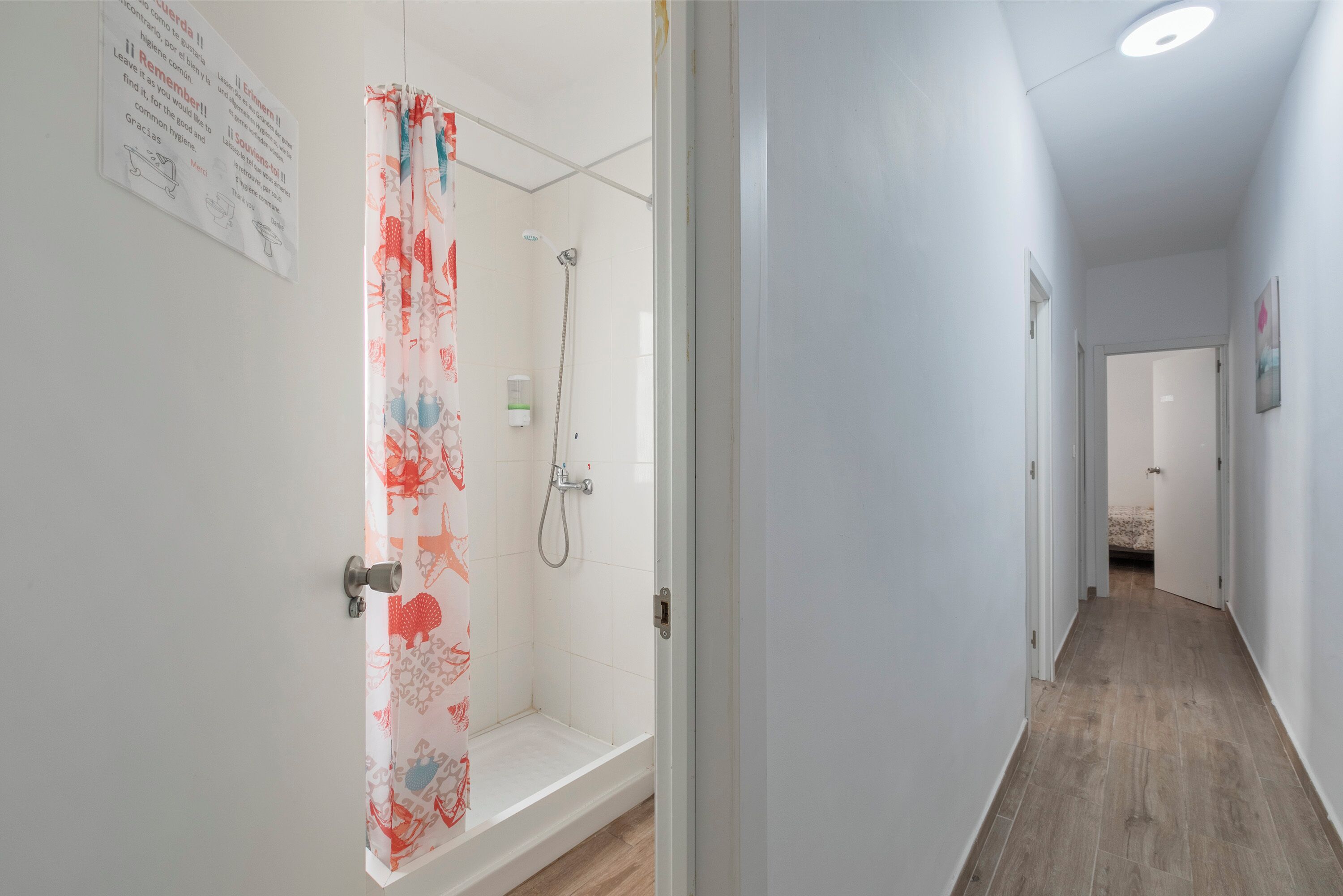 A narrow hallway with a shower area on the left, featuring a shower curtain with a floral pattern.