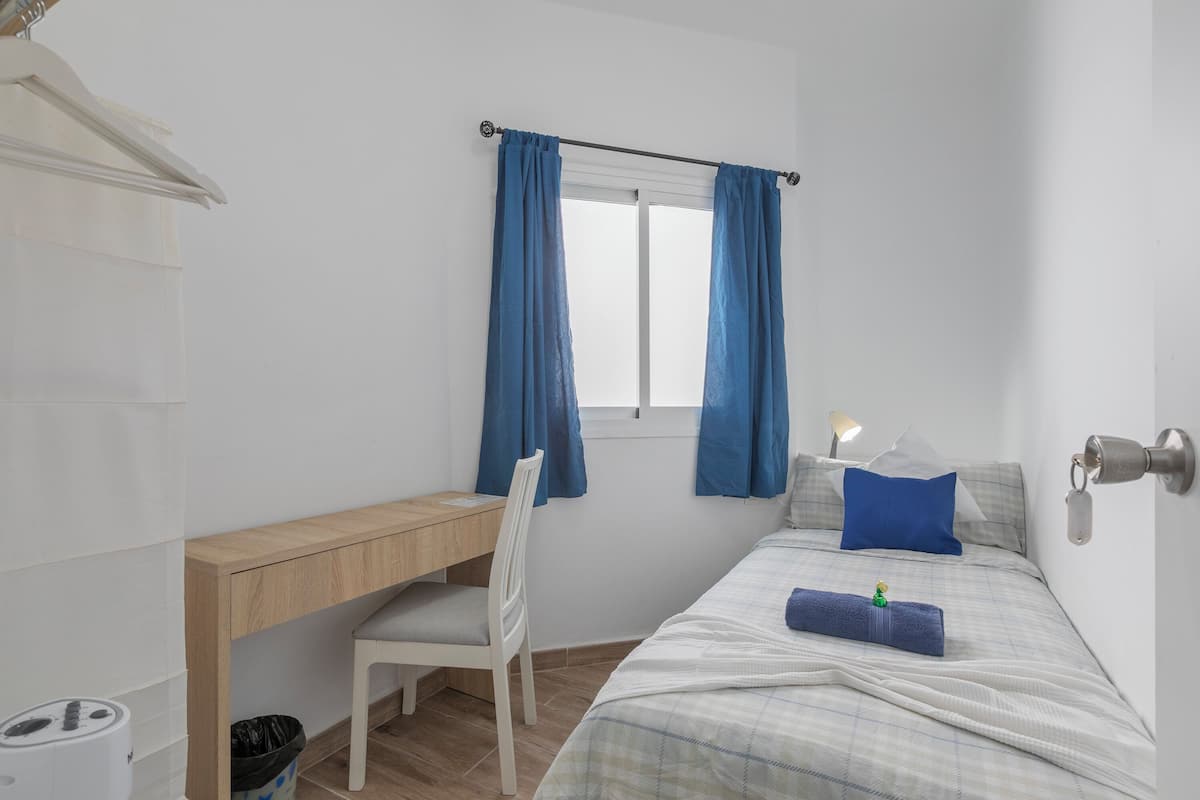 A small, tidy room with a bed, a desk, and a chair.