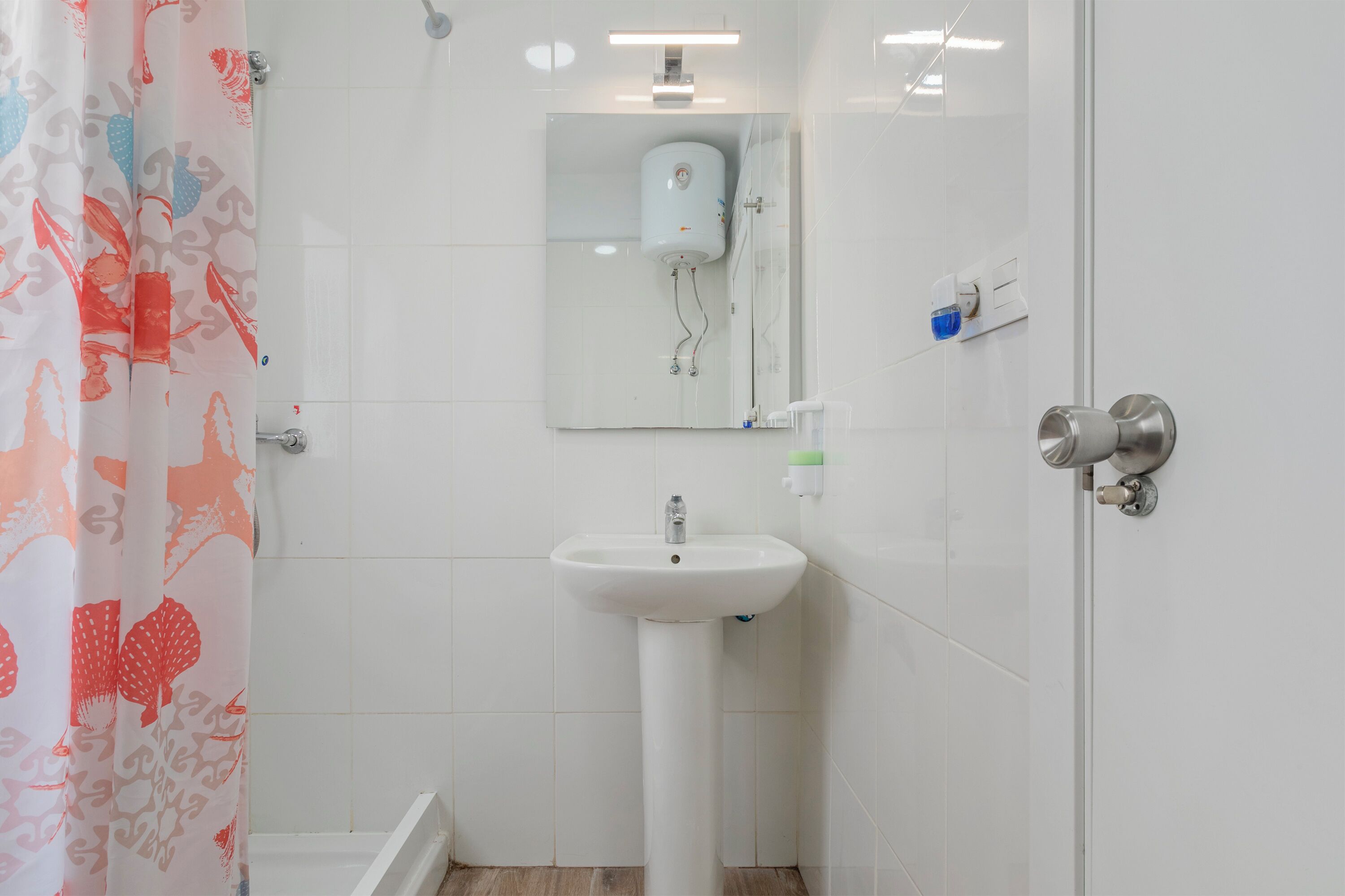 Une salle de bain avec un lavabo blanc, une douche et des toilettes.