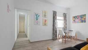 A modern living room with a dining area, featuring a wooden floor, white walls, and a black sofa. - TENERIFE URBAN ROOMS (Santa Cruz de Tenerife)