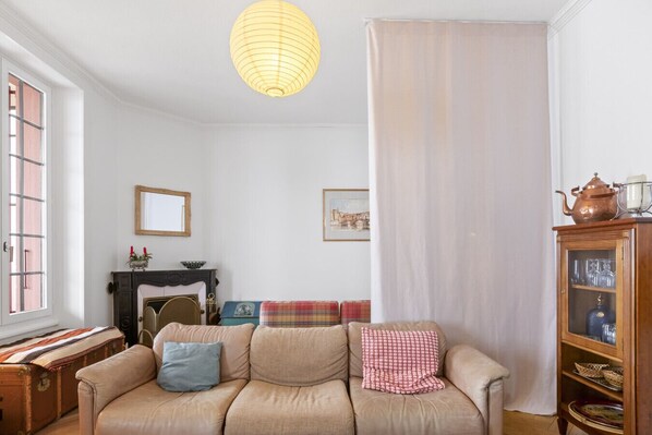 Una sala de estar acogedora con un sofá, una chimenea, una ventana y un aparador con cristalería.