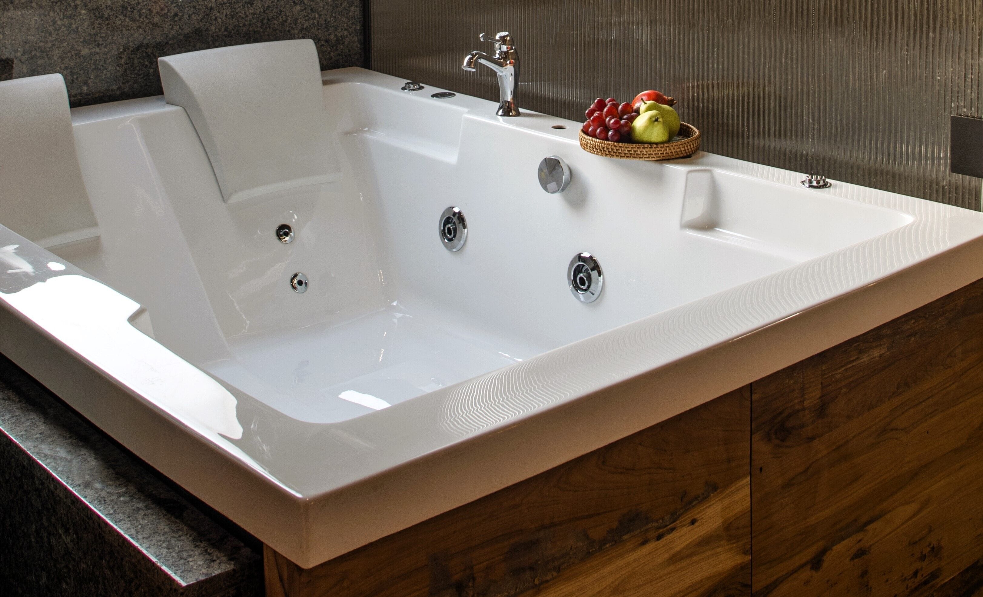 A large, rectangular bathtub with a modern faucet and multiple control knobs.