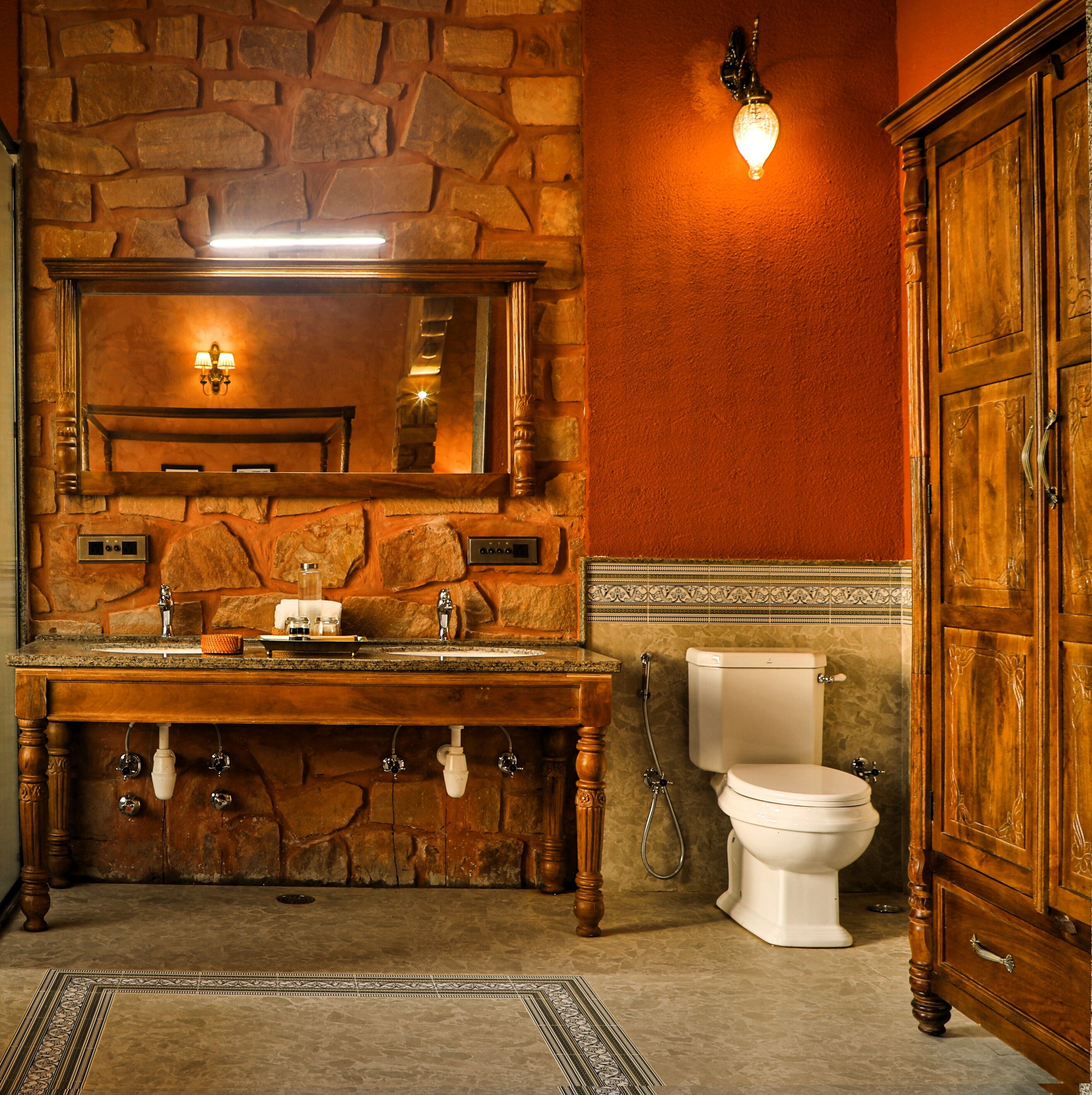 A bathroom with a stone wall, wooden vanity, and a white toilet.