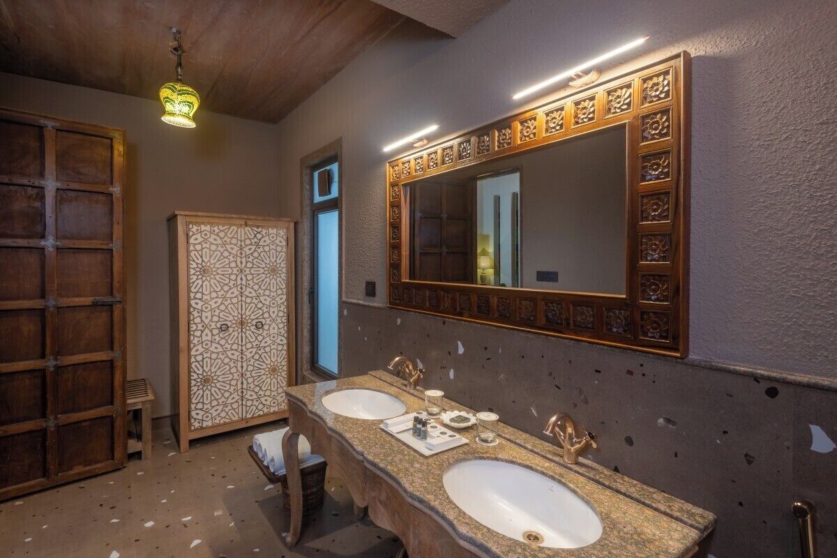 A bathroom with two sinks, a large mirror, and a decorative cabinet.