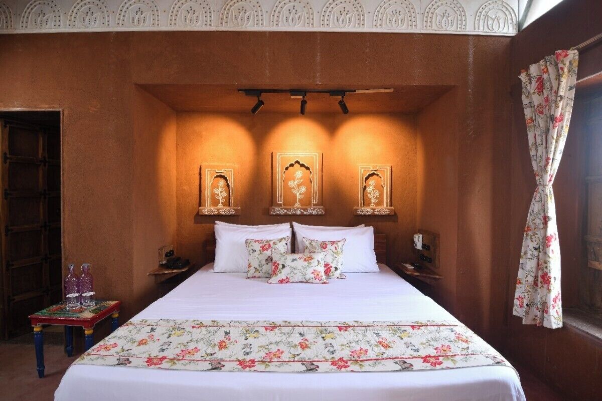 Une chambre à coucher avec un grand lit, une literie à motifs floraux et des appliques murales décoratives.