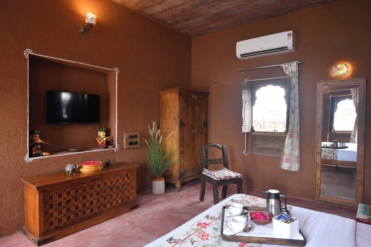 A room with a television, wooden cabinet, potted plant, chair, and a table with a tray of items.