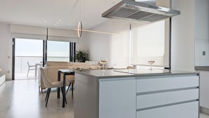 A modern kitchen with a central island, a dining area with chairs, and a view of the outdoors. - SUNSET CLIFFS top apartment (Benidorm)