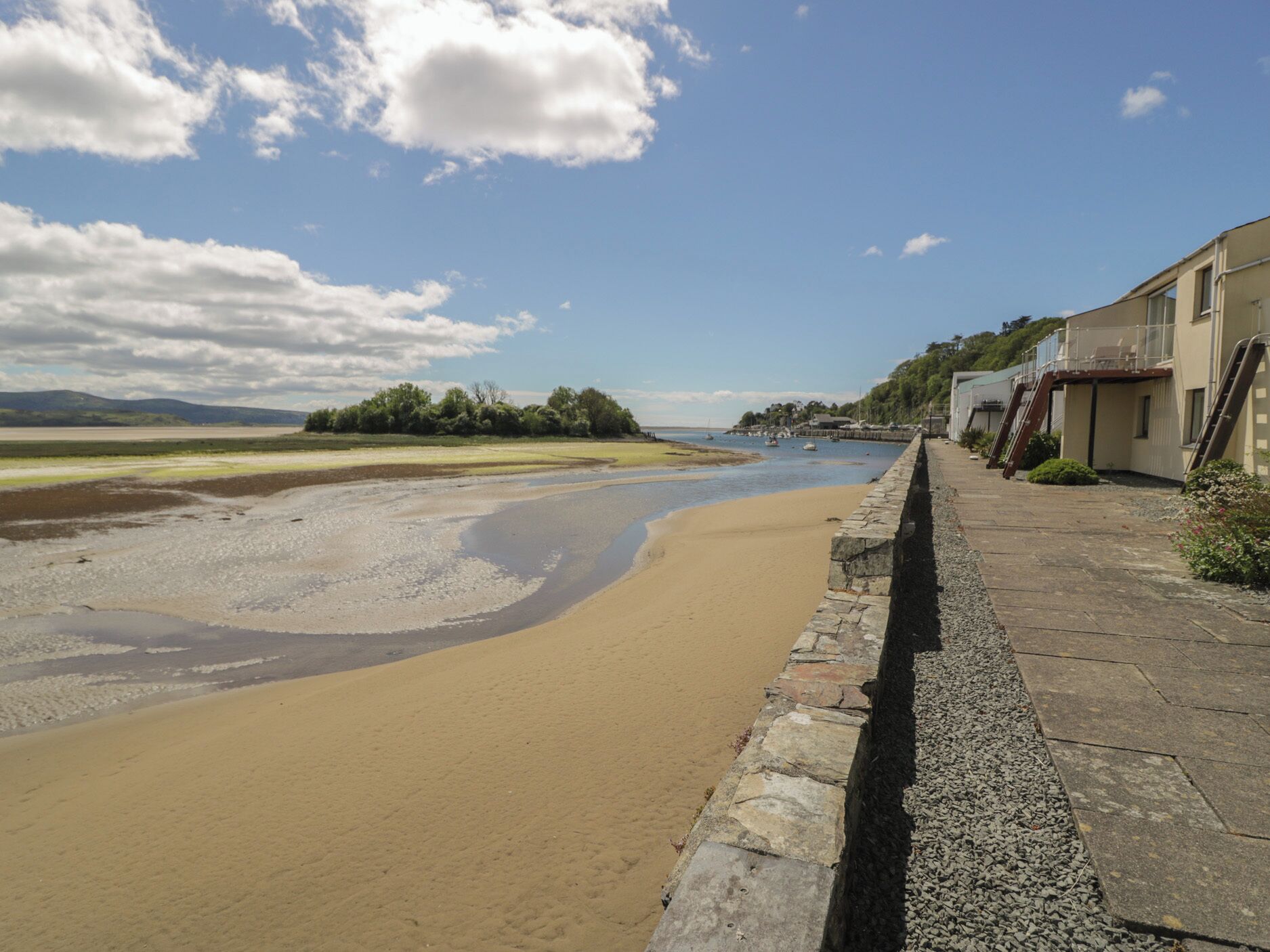 Una zona costera con una playa arenosa, un muro de piedra y edificios con balcones.