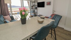A modern kitchen with a dining table, chairs, a potted plant, and a TV mounted on the wall. - Lan y Mor (Porthmadog)
