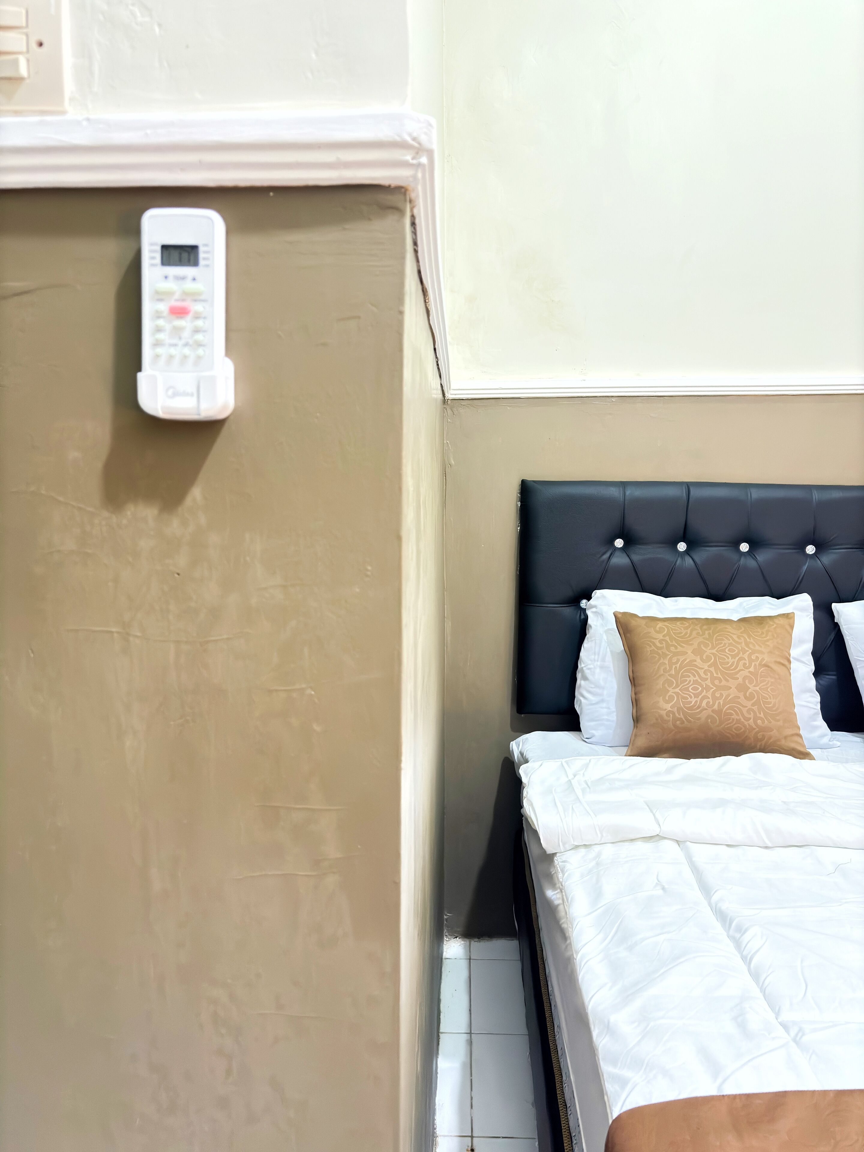 A hotel room with a bed, a control panel, and a wall with a textured finish.