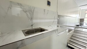 A bathroom with a marble sink and a white tiled wall. - Griya Inn (Semarang)