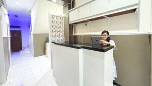 A hotel reception area with a counter, a door marked with the number 3, and a patterned wall. - Griya Inn (Semarang)