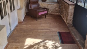 Une pièce aux murs de pierre, dotée d’un plancher en bois, d’un fauteuil en cuir et d’une fenêtre offrant une vue agréable.