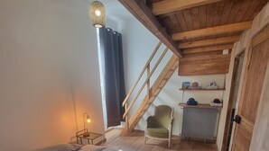 Une chambre à coucher comprenant un lit, une chaise, un radiateur, un escalier en bois et une étagère avec des serviettes.