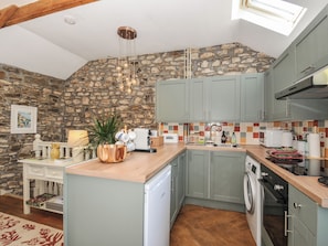 A kitchen with stone walls, a wooden island, and modern appliances.