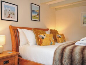 A bedroom with a wooden headboard, white bedding, and two framed pictures on the wall. - The Mill (Lostwithiel)