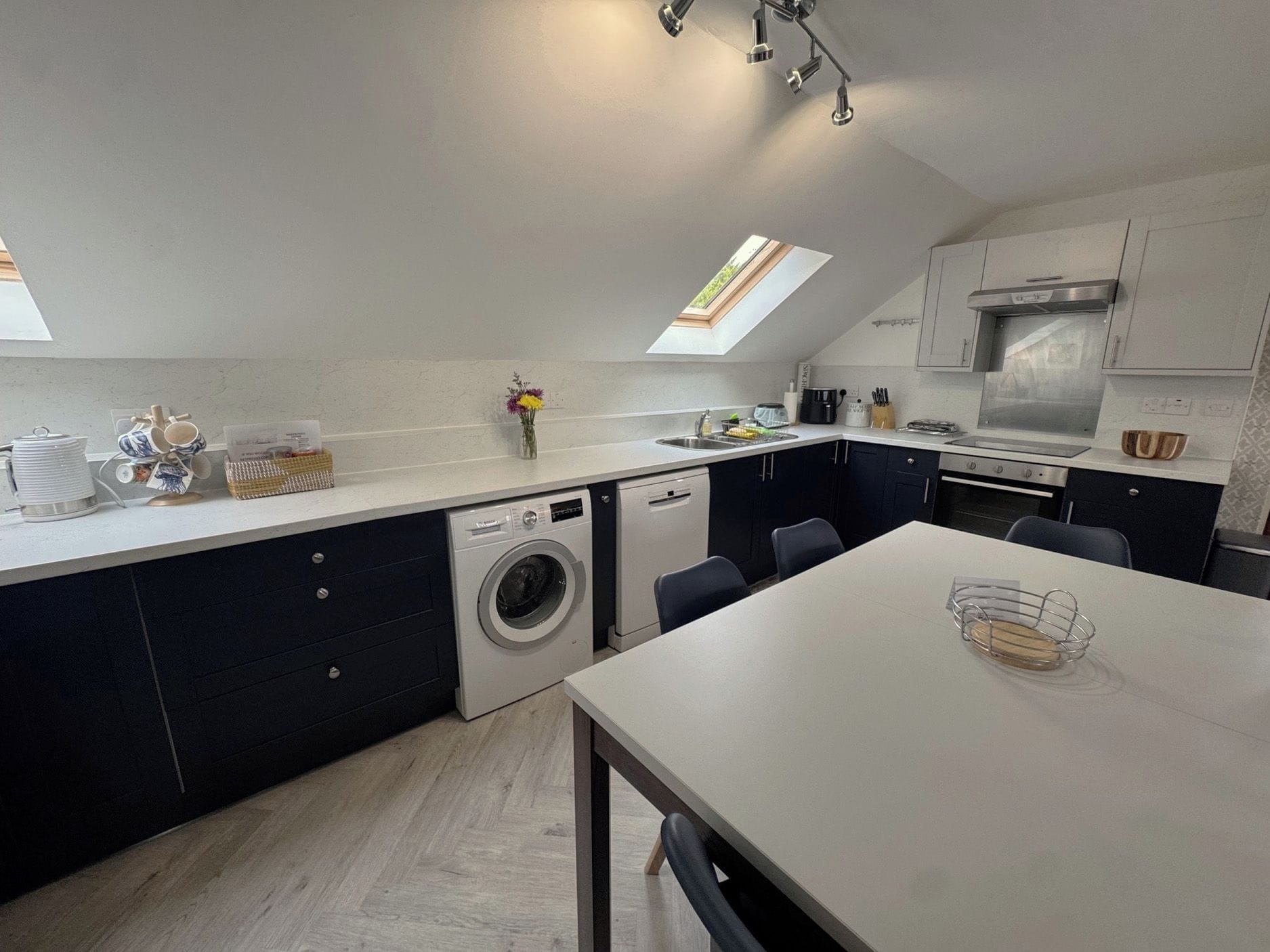 Une cuisine moderne dotée d’un lave-linge encastré, d’un coin repas et de fenêtres de toit.