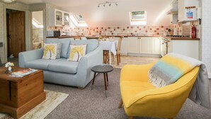 Een knus woongedeelte met een bank, fauteuil, eettafel en kitchenette.