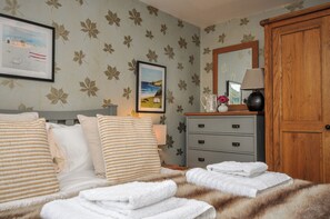 A bedroom with a bed, pillows, a dresser, and a mirror.