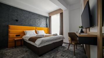 Una habitación de hotel moderna con una cama grande, un escritorio y un televisor.