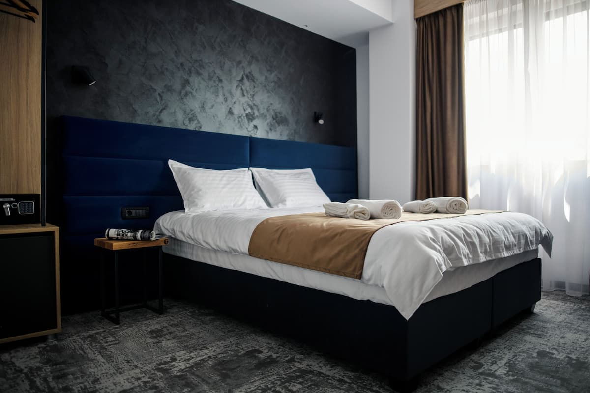 Una habitación de hotel moderna con una cama grande, una mesita de noche y un armario.