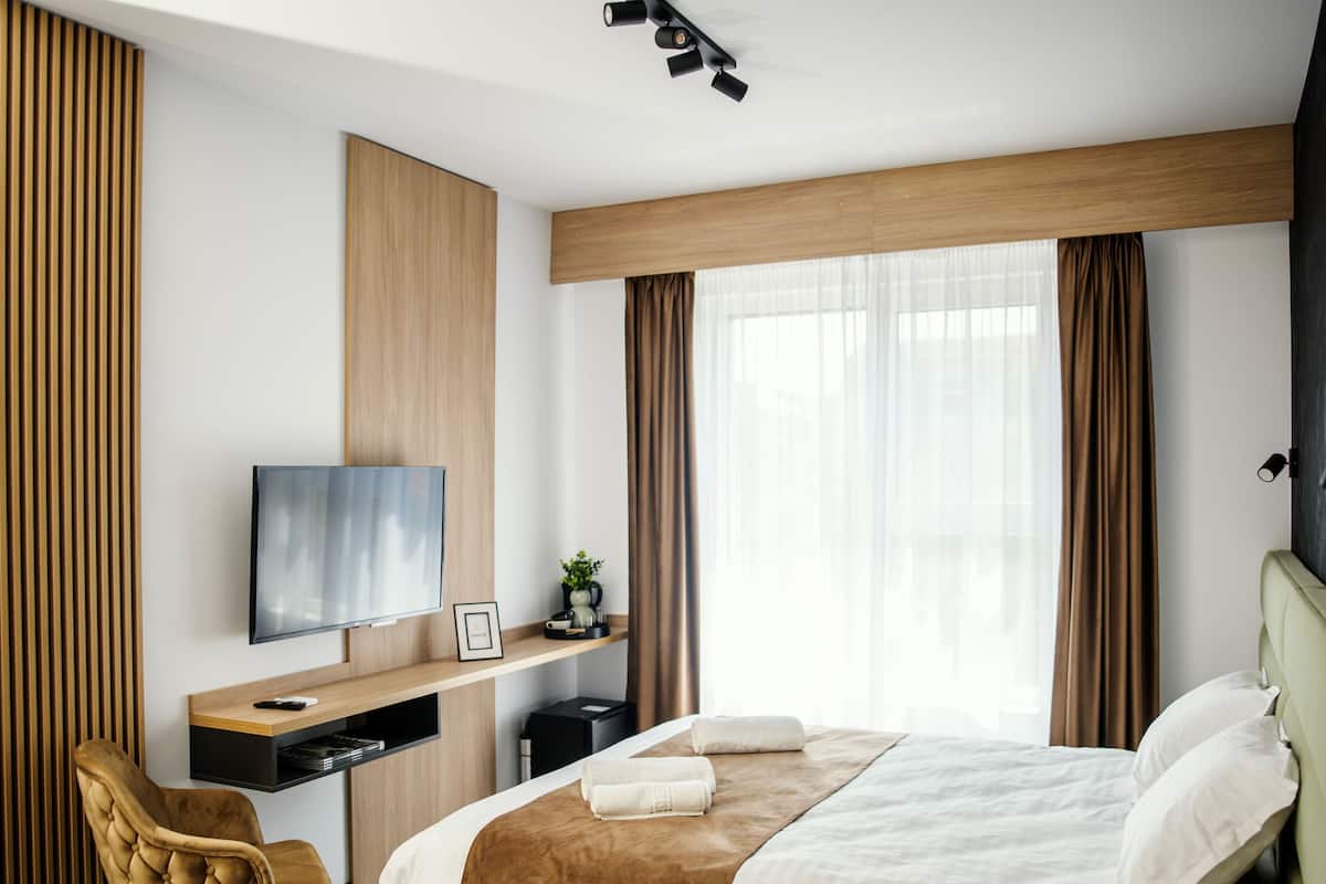 Una habitación de hotel moderna con cama, televisor, escritorio y silla.