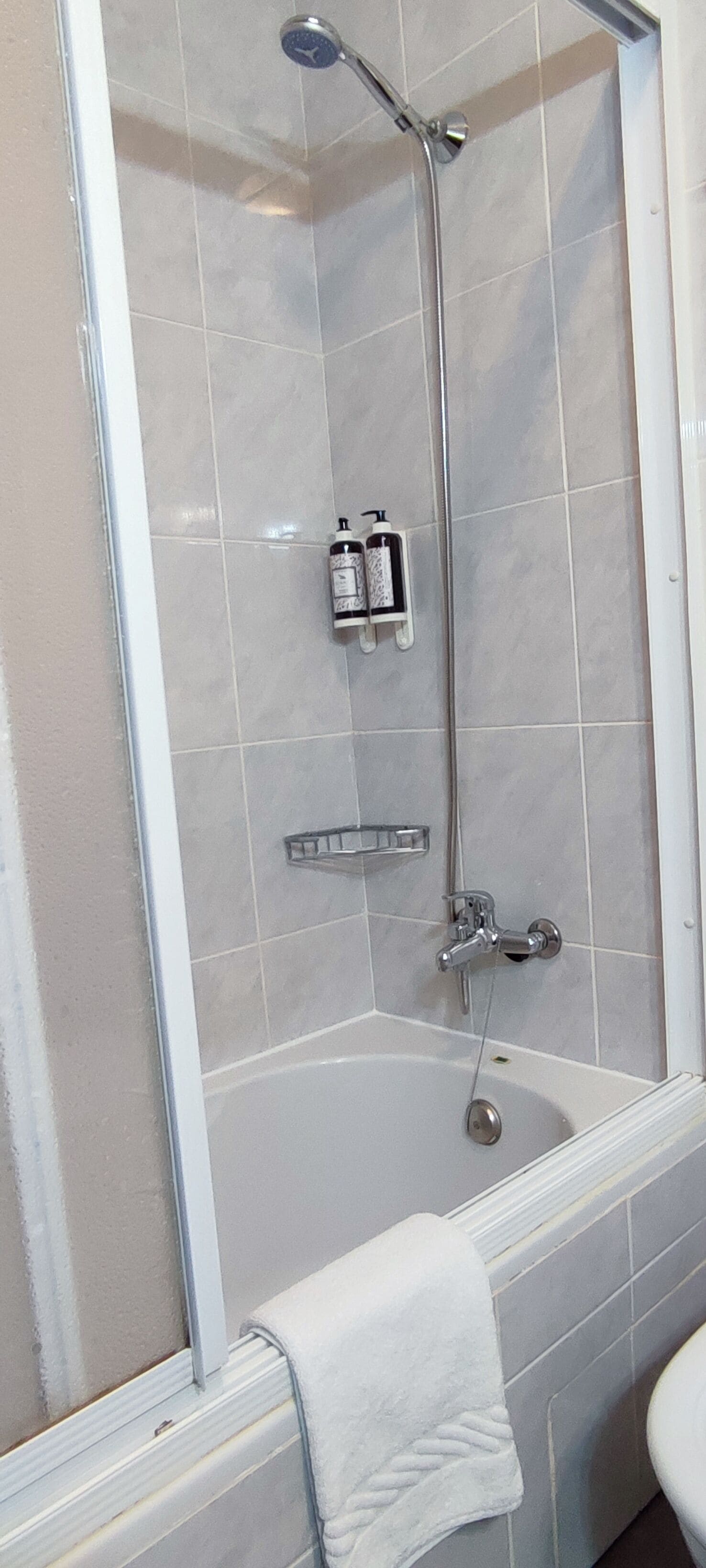 Un bany modern amb plat de dutxa envoltat de vidre, una banyera i un vàter.