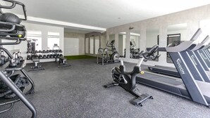 Un gimnasio con cintas de correr, máquinas de pesas y pesas libres.