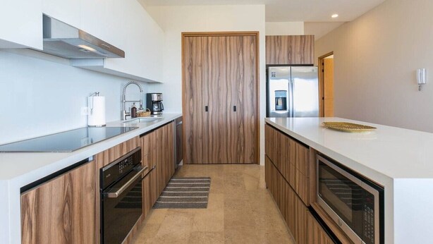 Una cocina moderna con gabinetes de madera, electrodomésticos de acero inoxidable y una isla central.