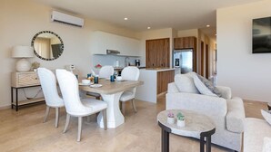 Una sala moderna con comedor, cocina y un espejo grande.
