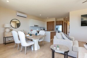 A modern living room with a dining area, kitchen, and a large mirror.