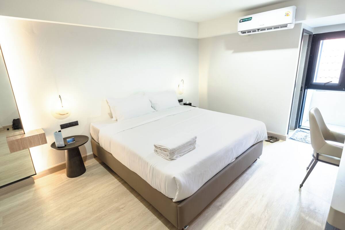 Een moderne hotelkamer met een groot bed, nachtkastjes, een bureau en een airconditioning.