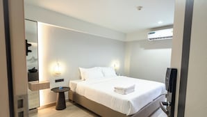 Une chambre d’hôtel moderne, équipée d’un lit, d’une table de chevet et d’un miroir.