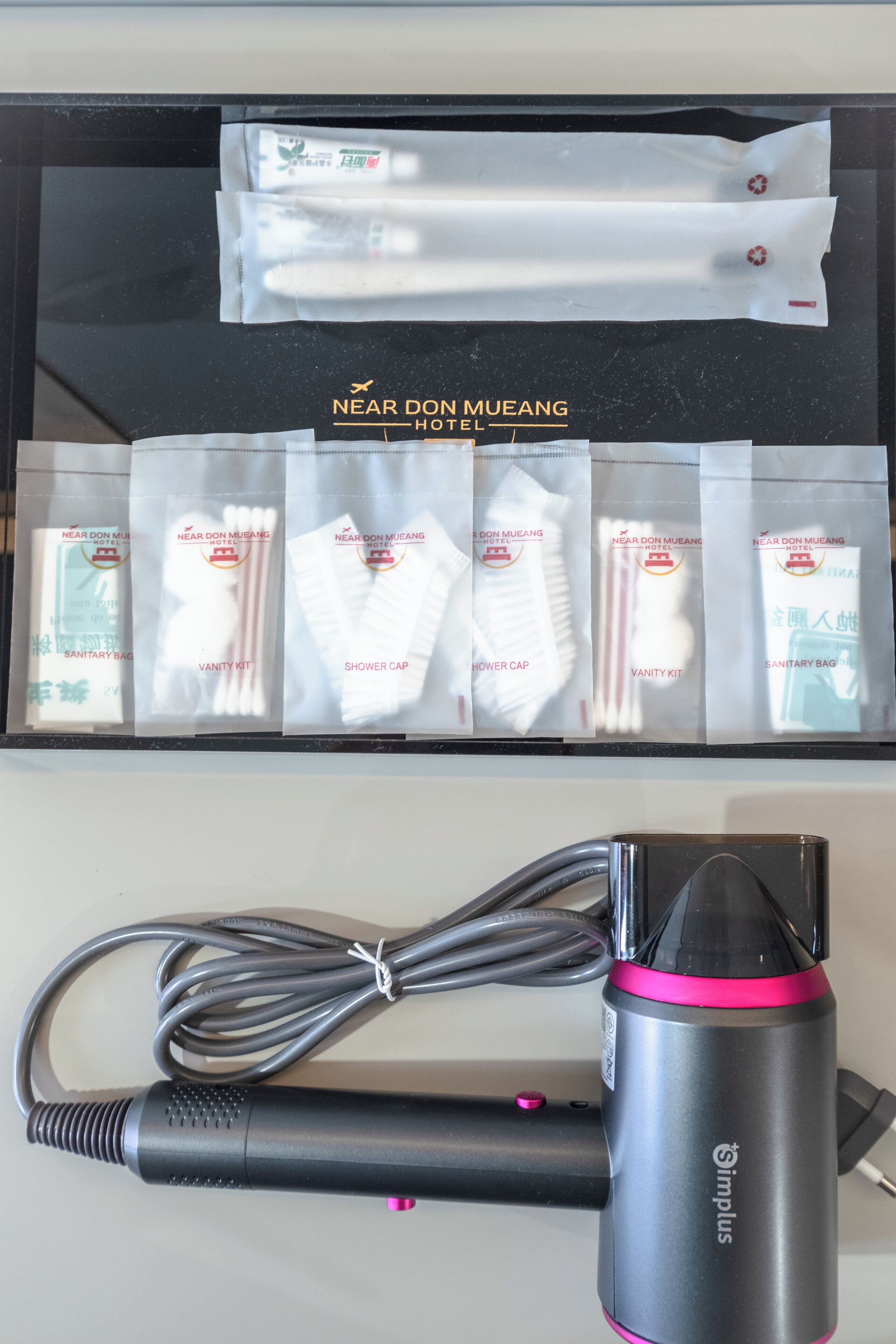 A hotel room with a black box containing sanitary bags, a vanity kit, and a shower cap.