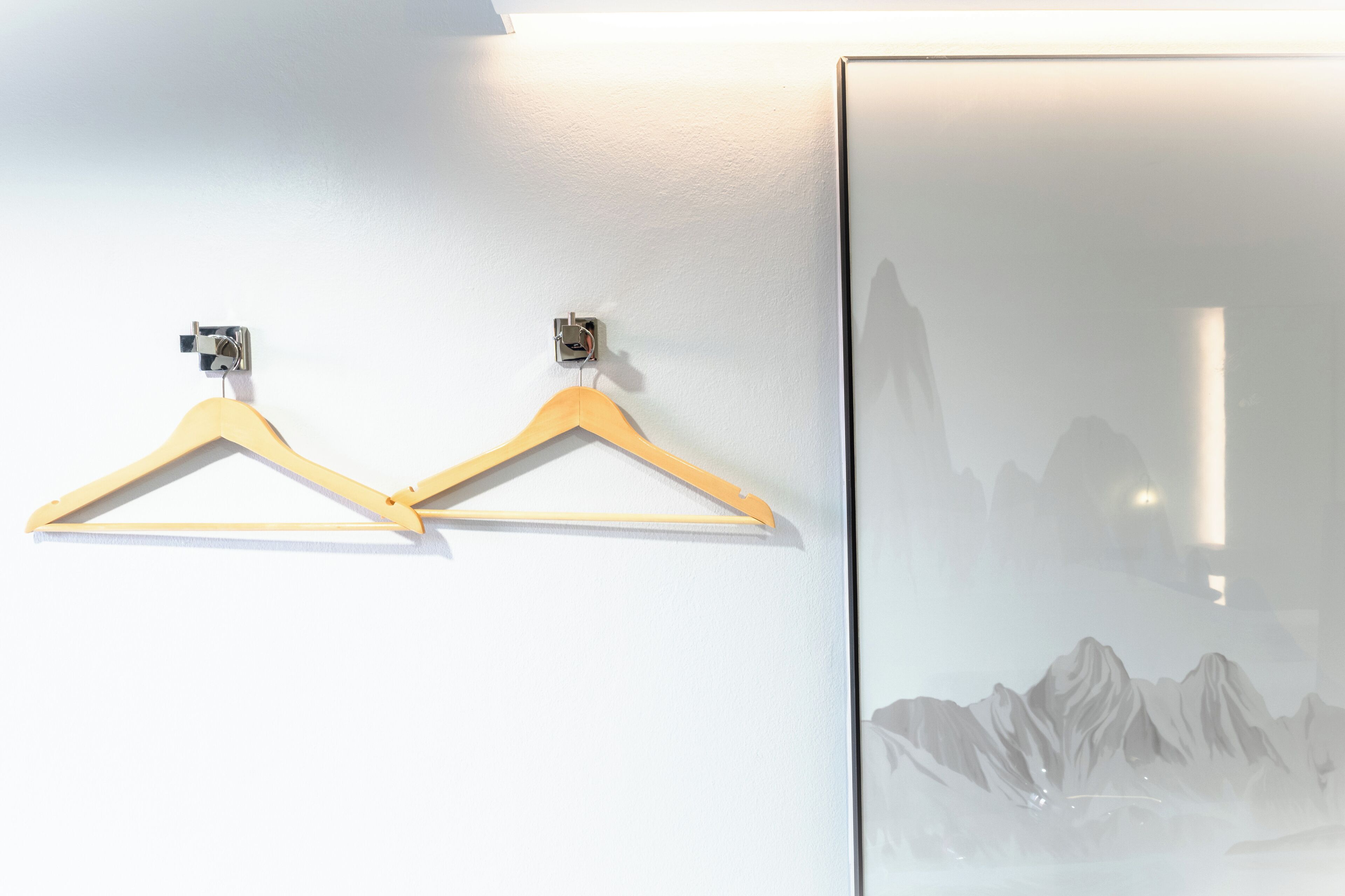 Ein an der Wand befestigter Holzhalter mit Metallclip und eine Glastür mit Blick auf Berge.