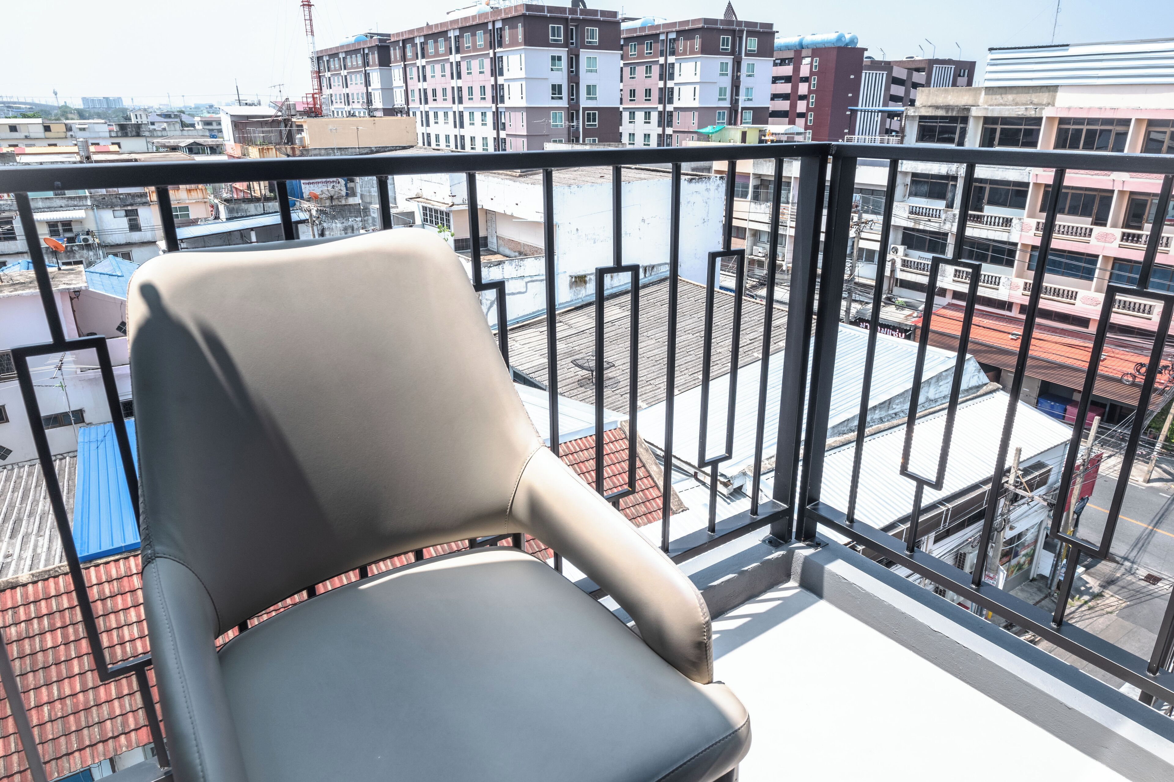 En balkon med en stol, der giver udsigt over bybilledet med flere bygninger.