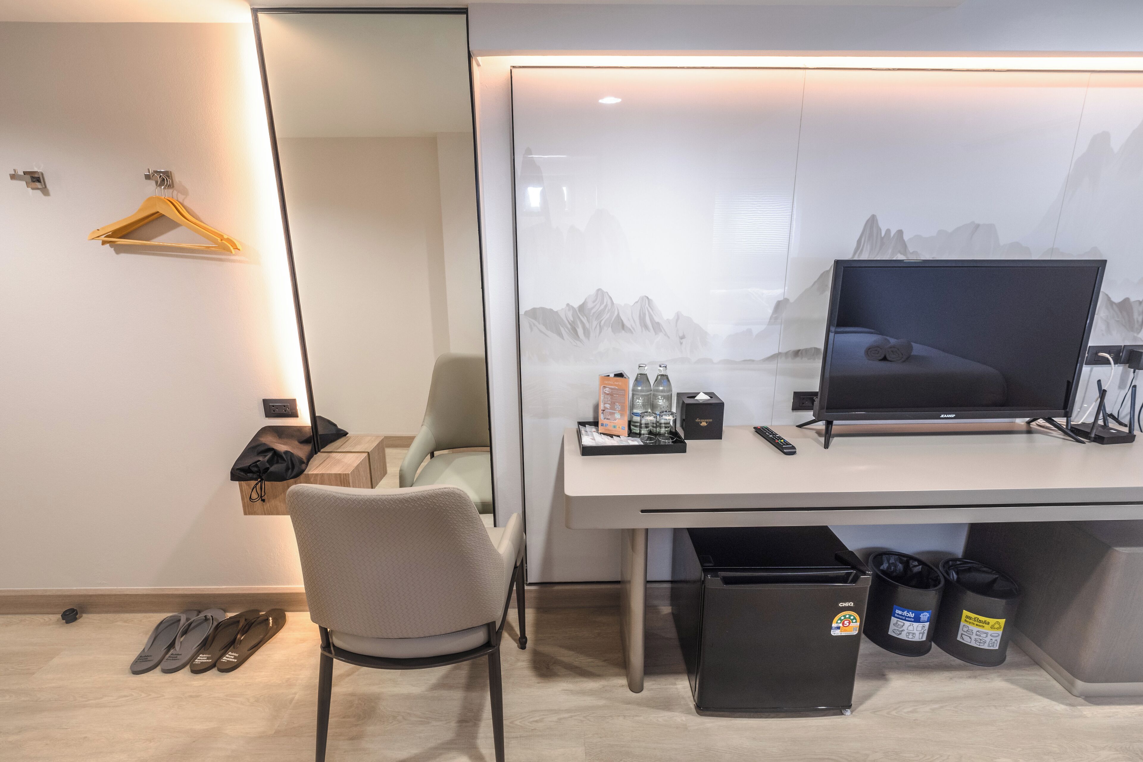A modern hotel room with a desk, chair, and a large window with a mountain view.