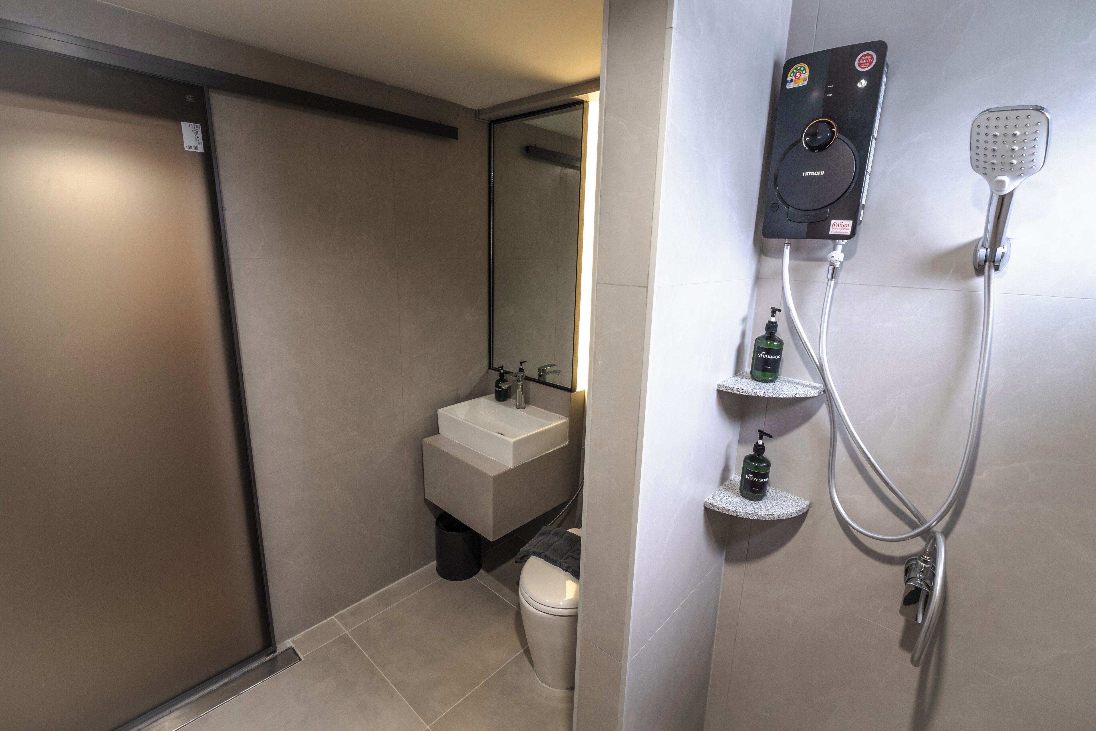 Une salle de bain moderne équipée de toilettes, d’un lavabo et d’une douchette fixée au mur.