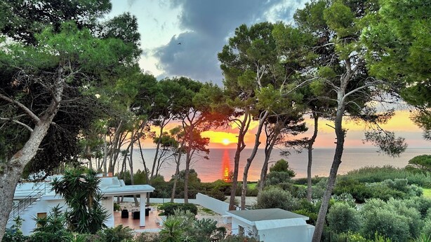 A coastal property with a view of the sunset over the sea, surrounded by lush greenery and modern architecture. - Your Stay at Villa Calipso - The Perfect Family Escape by the Sea (Taranto)