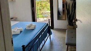 A bedroom with a bed, a bench, a potted plant, a TV, and a view of the outdoors. - Your Stay at Villa Calipso - The Perfect Family Escape by the Sea (Taranto)