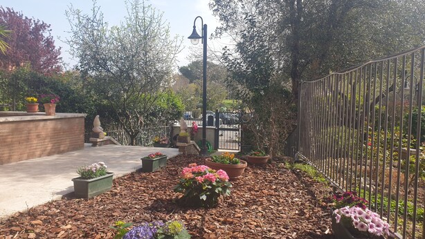 A garden with potted plants, a metal fence, and a street lamp. - Villa "Domus Roma" - Room Spanish Steps (Roma)