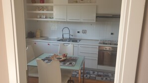 A compact kitchen with white cabinets, a stainless steel sink, and a built-in oven. - Villa "Domus Roma" - Room Spanish Steps (Roma)
