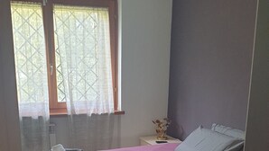 A bedroom with a bed, a nightstand, a window with curtains, and a wall-mounted air conditioner. - Villa "Domus Roma" - Room Spanish Steps (Roma)