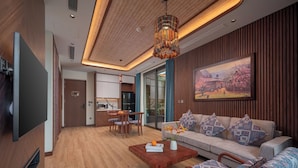 Una sala moderna con sofá, sillas, una mesa de centro, televisor y un comedor con mesa y sillas.