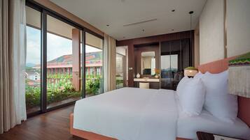 A hotel room with a large bed, a desk, and a view of a building with colorful roofs.