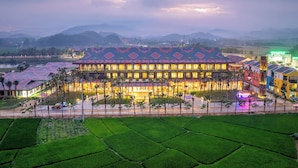Un hotel con techo estampado, rodeado de campos verdes y montañas.