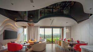 Amplia sala de estar con diseño moderno, que incluye una gran mesa de comedor preparada para seis personas, un conjunto de asientos cómodo y un ventanal con vistas panorámicas.